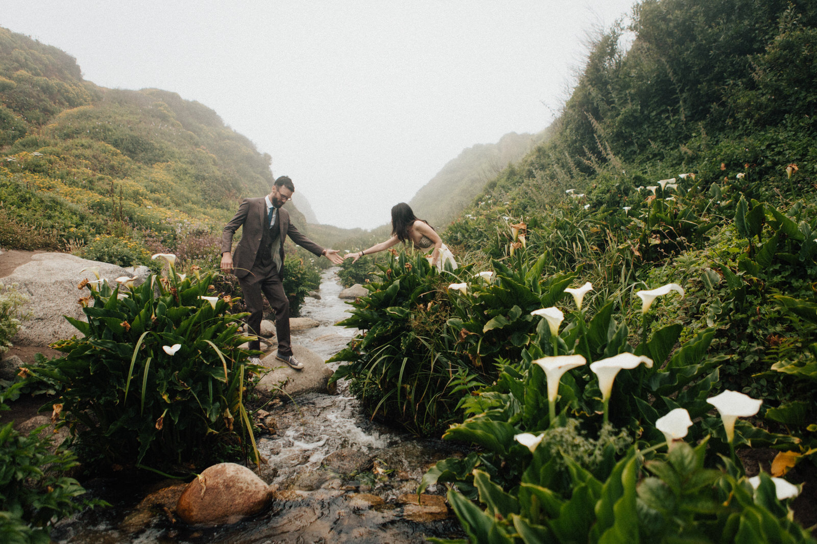 Couple in Cala Lily valley crossing creek