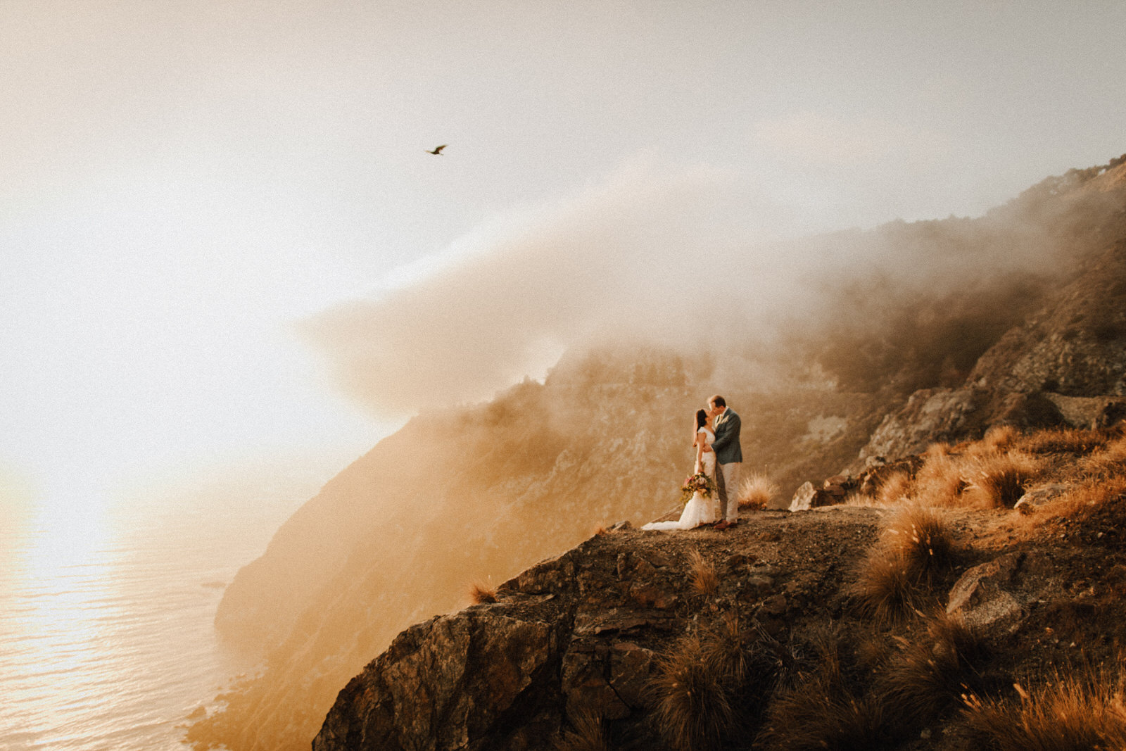 Elopement couple kissing on cliff in Big Sur during sunset