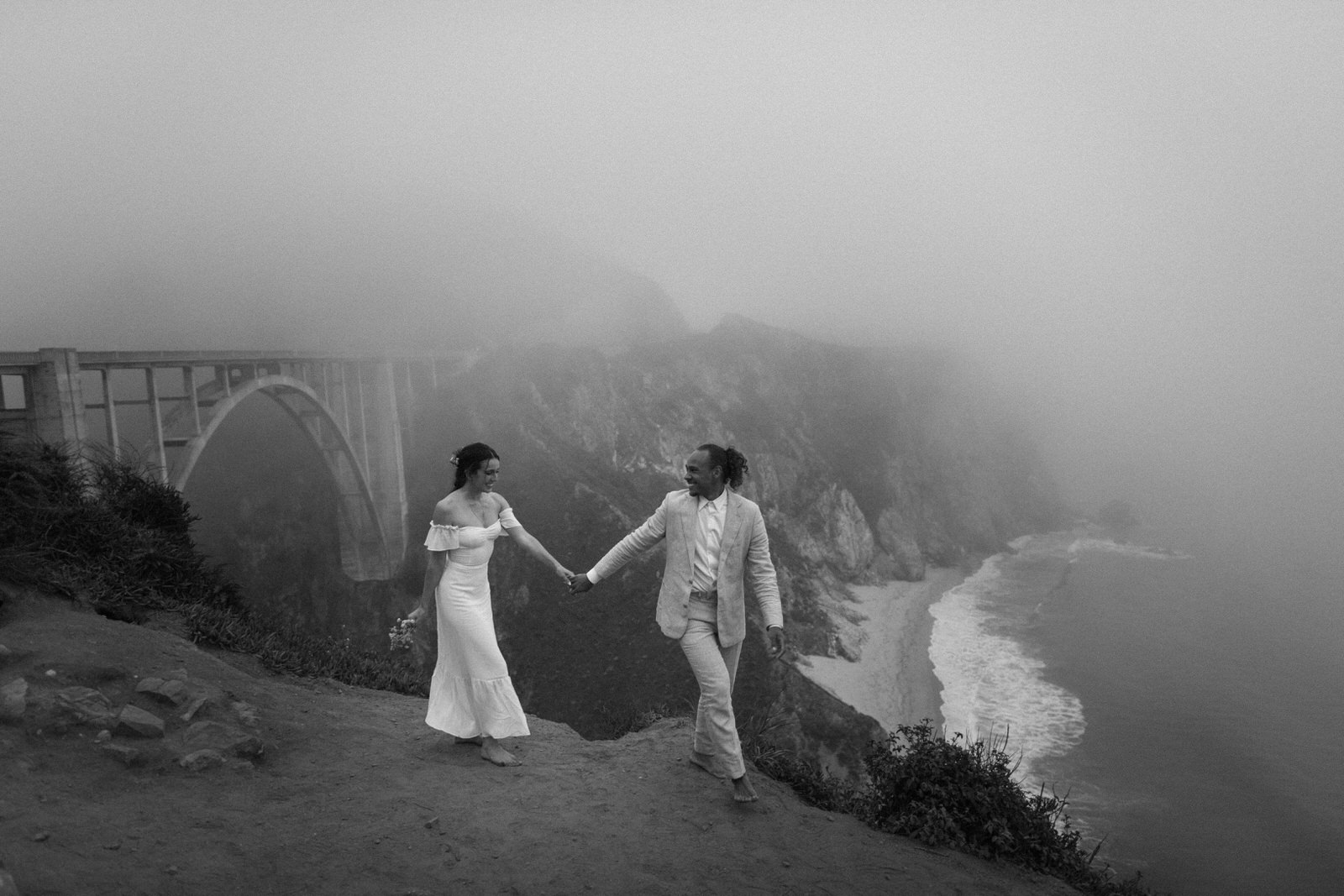 Wedding couple walking along cliff in Big Sur
