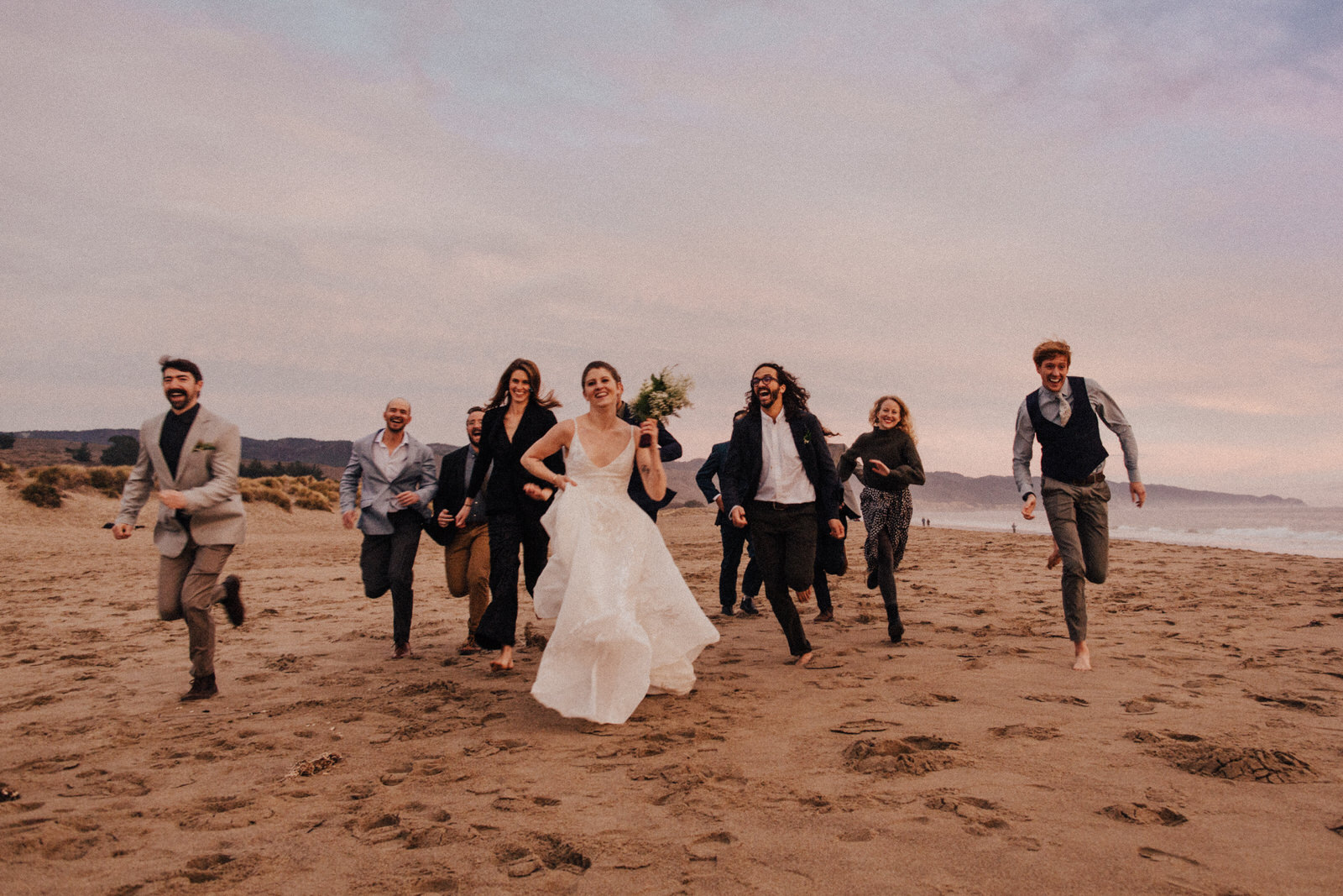 Wedding party running on beach