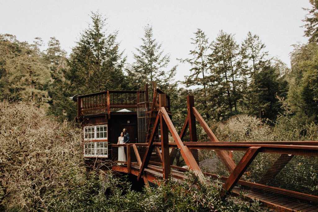 couple standing on a wooden bridge looking out into nature