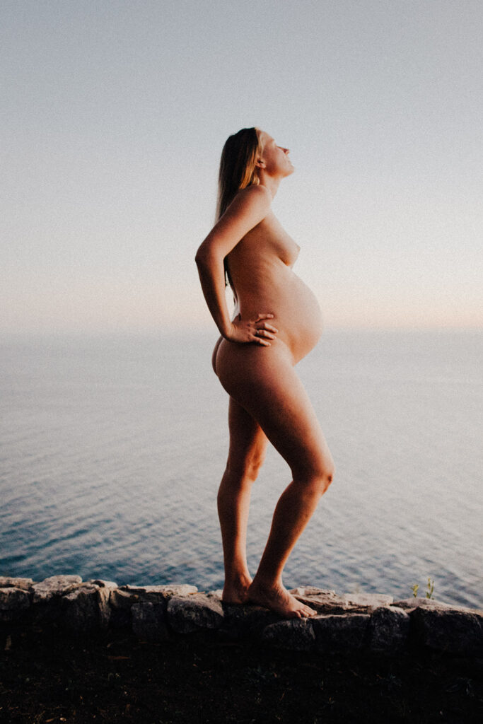 Pregnant woman standing above ocean in Big Sur during sunset